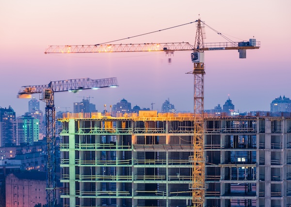 multi-unit building under construction with a cityscape background