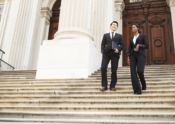 Two government workers walking down the outside stairs of a government building. 