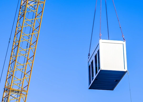 HousingDensityMandates-Internal3-600x428 Crane placing a prefabricated office module onto a construction project.